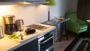 Une cuisine moderne équipée d’une machine à café, d’une plaque de cuisson à induction et d’une chaise verte.