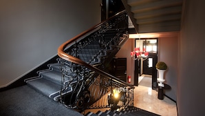 A staircase with a wooden handrail and metal balusters, leading to a landing with a door and a potted plant. - Frogner House - Skovveien (Oslo)