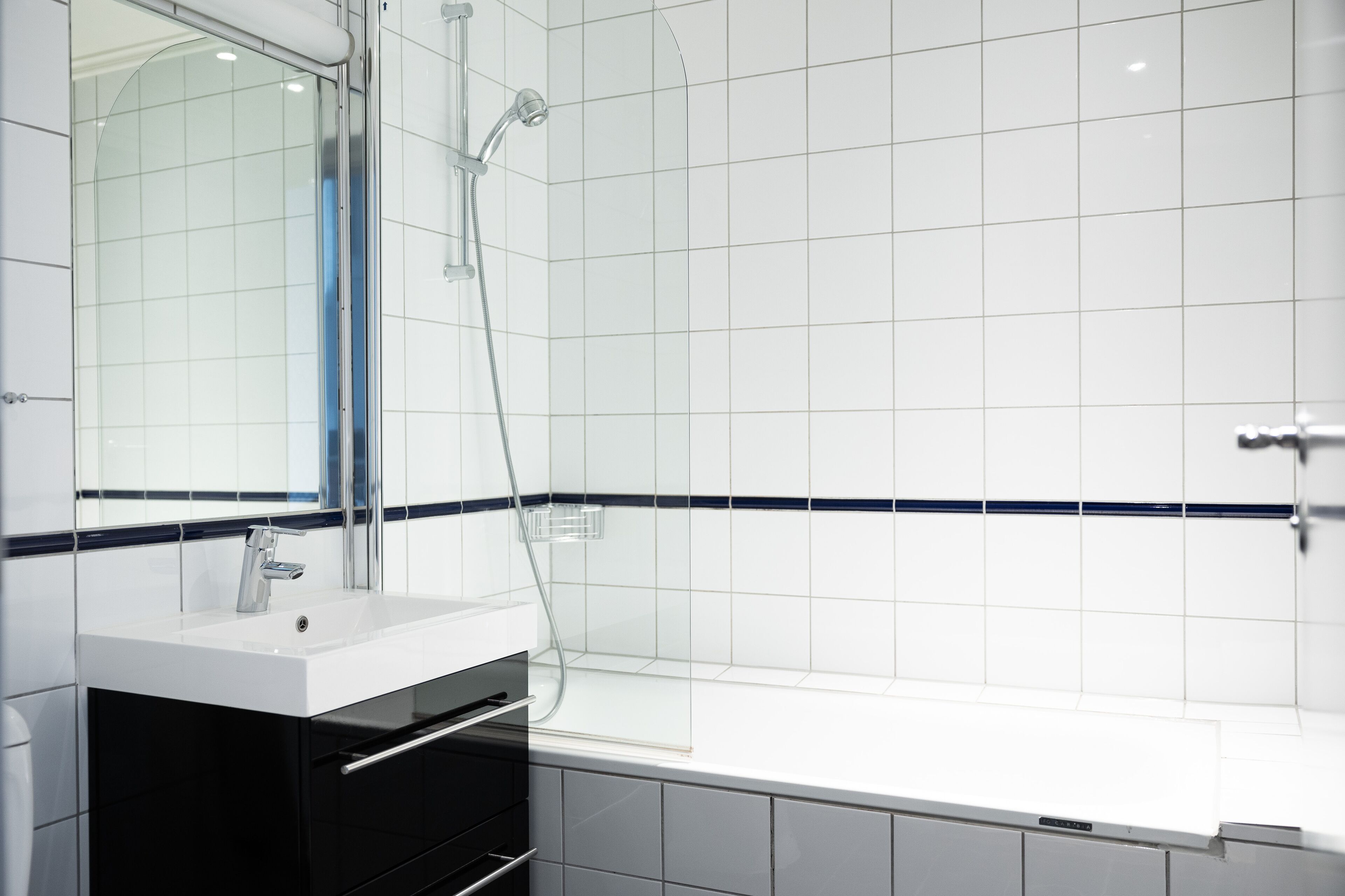 A modern bathroom with a white sink, mirror, and bathtub.