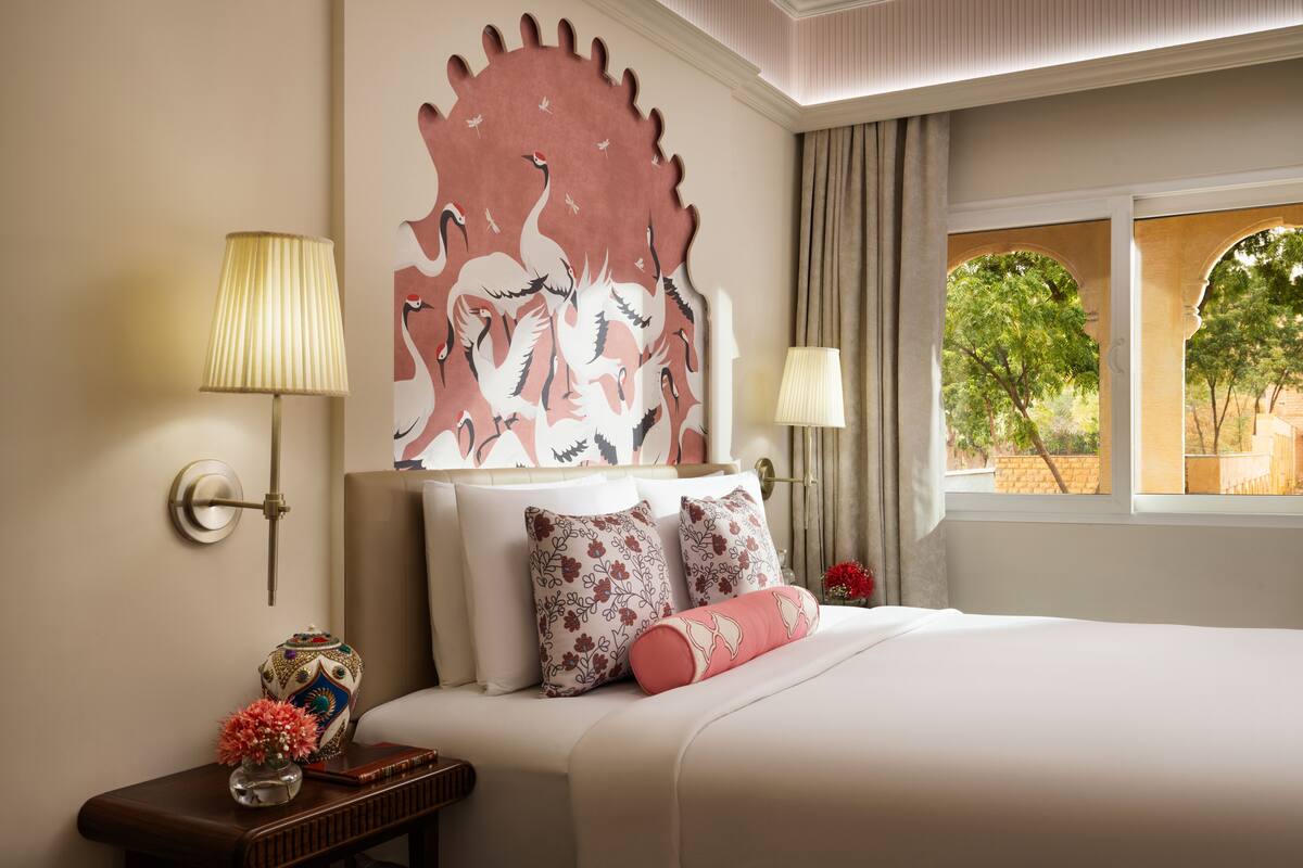 Une chambre d’hôtel avec un grand lit, deux lampes de chevet, un élément décoratif mural et une vue sur l’extérieur.