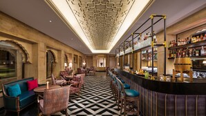 A bar area with a checkered floor, bar stools, and shelves of liquor bottles. - Taj Gorbandh Palace, Jaisalmer (Jaisalmer)