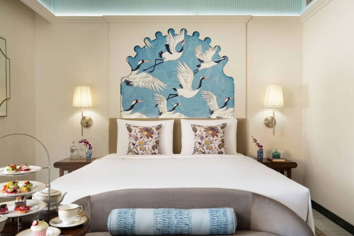 Une chambre d’hôtel comprenant un lit, deux tables de chevet, un élément décoratif mural et une petite table avec un service à thé.