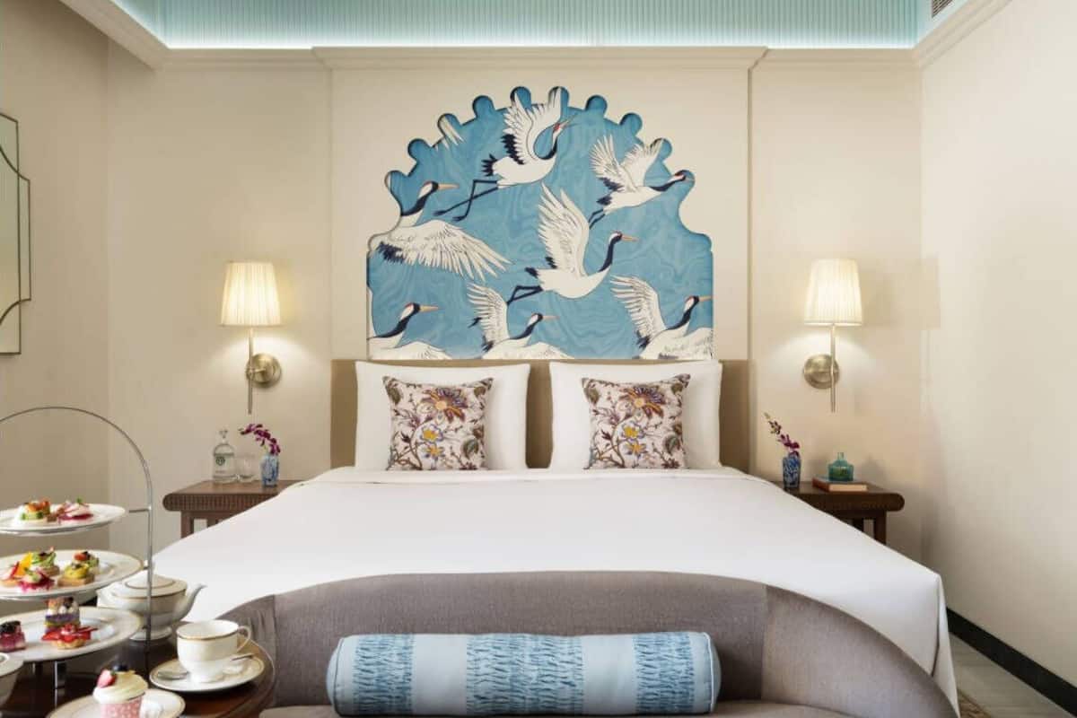 Une chambre d’hôtel comprenant un lit, deux tables de chevet, un élément décoratif mural et une petite table avec un service à thé.