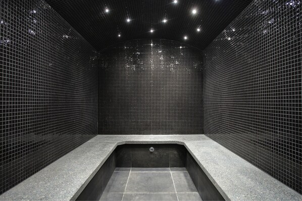 A modern bathroom with a rectangular bathtub, tiled walls, and a ceiling with recessed lighting. - Kreutzwald Hotel Tallinn (Tallinn)