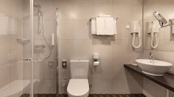 Een moderne badkamer met een douchecabine van glas, een wit toilet, een wastafel met spiegel en een handdoekhouder.