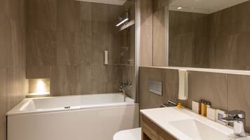A modern bathroom with a bathtub, toilet, and vanity.