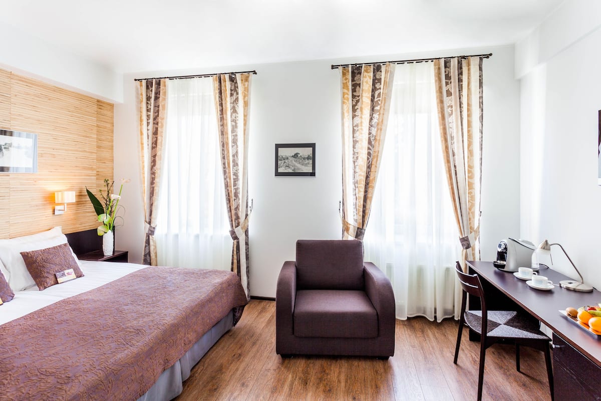 Ein Hotelzimmer mit Bett, Schreibtisch mit Stuhl, Lampe und einem Bild an der Wand.