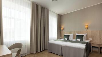 A hotel room with a bed, bedside tables, a desk, and a chair.