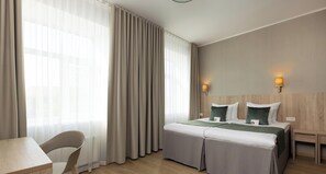 Una habitación de hotel con cama, mesitas de noche, escritorio y silla.