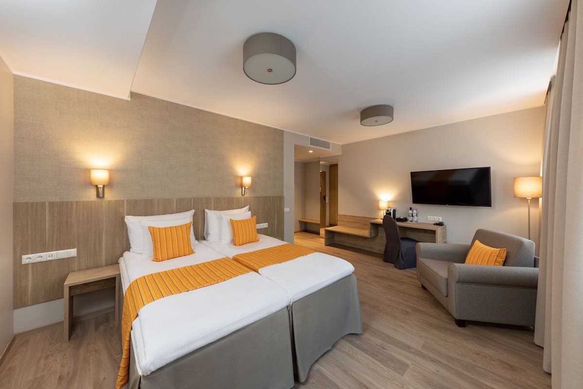 Ein modernes Hotelzimmer mit einem großen Bett, einem Schreibtisch, einer Couch und einem Fernseher.