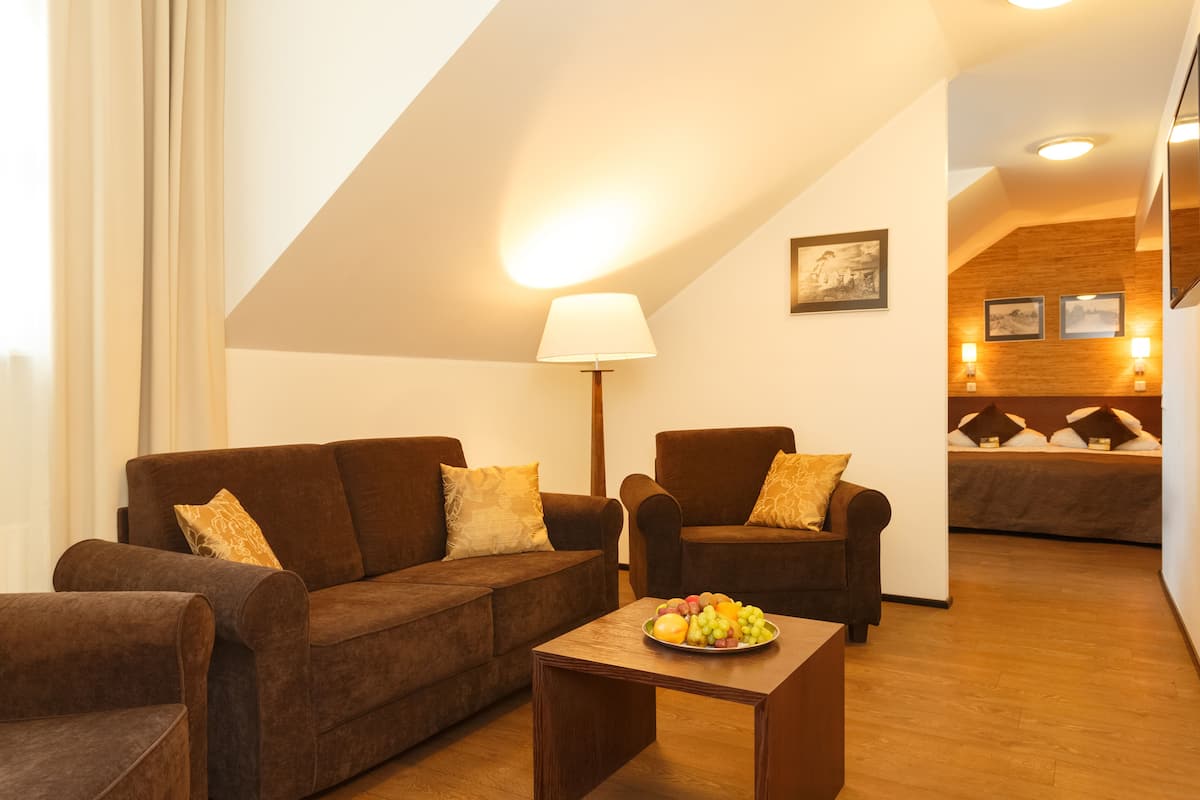 Ein modernes Wohnzimmer mit einer braunen Sofagarnitur, einem kleinen Holztisch mit Obst und einer Lampe.