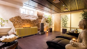 A modern spa area with a stone wall, a large white basin, and a statue of a meditating figure. - Kreutzwald Hotel Tallinn (Tallinn)