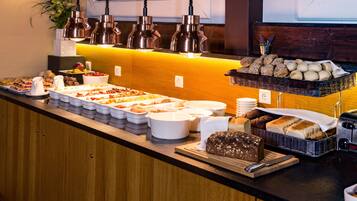A buffet counter with various food items and a cutting board with a knife.