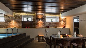 A modern kitchen with a brick wall, a built-in pool, and a dining area with wicker chairs. - Kreutzwald Hotel Tallinn (Tallinn)