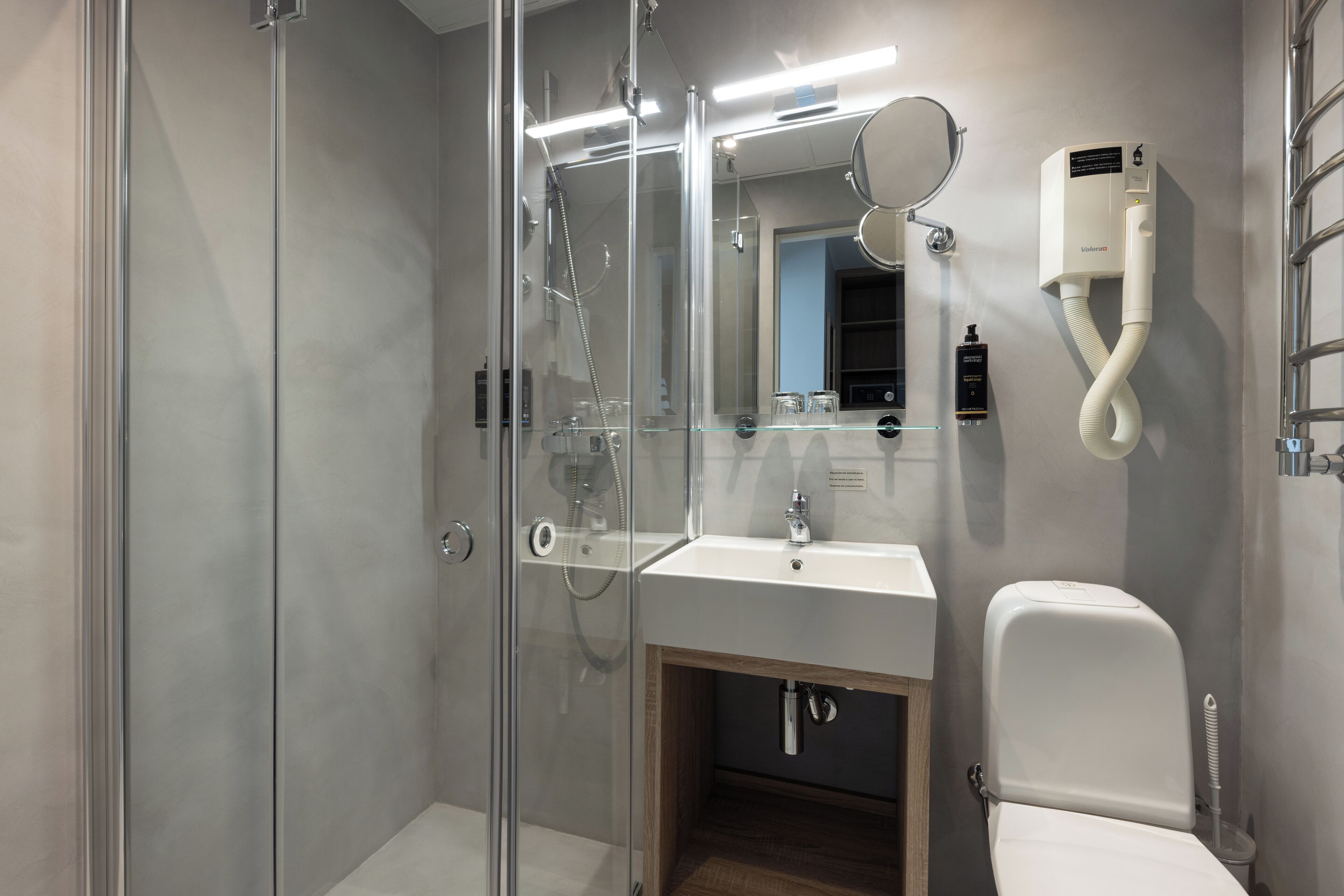 Un baño moderno con ducha de vidrio, un lavamanos blanco y un inodoro.