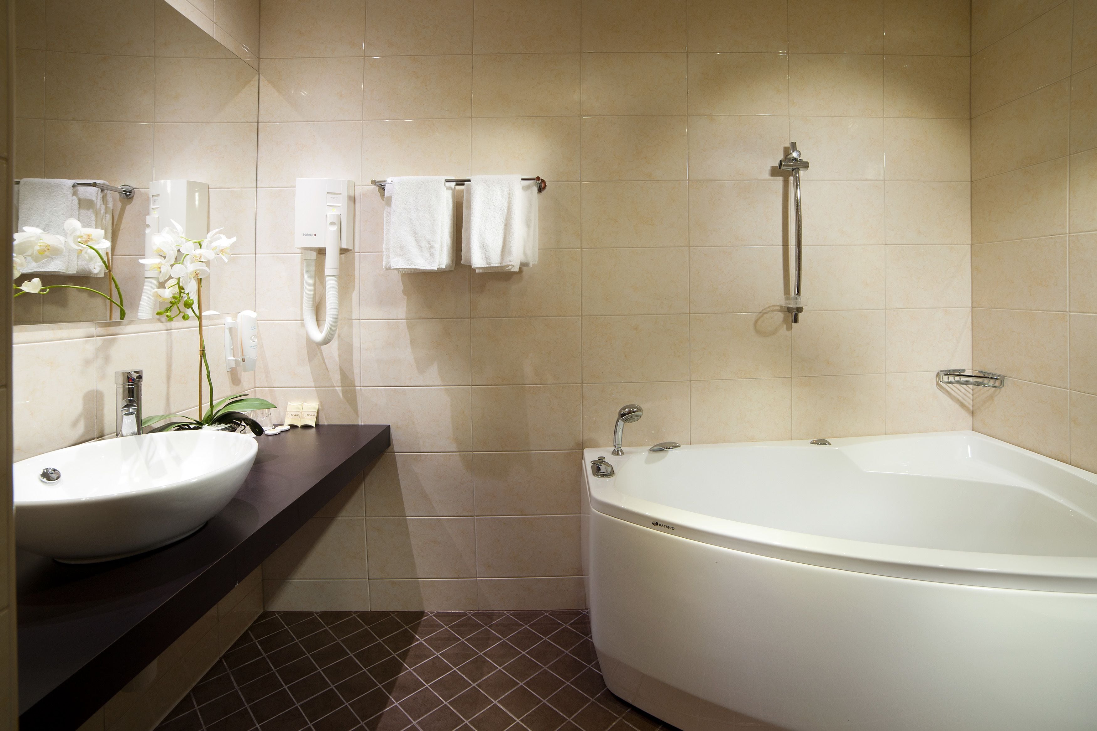 A modern bathroom with a large bathtub, a sink, and a mirror.
