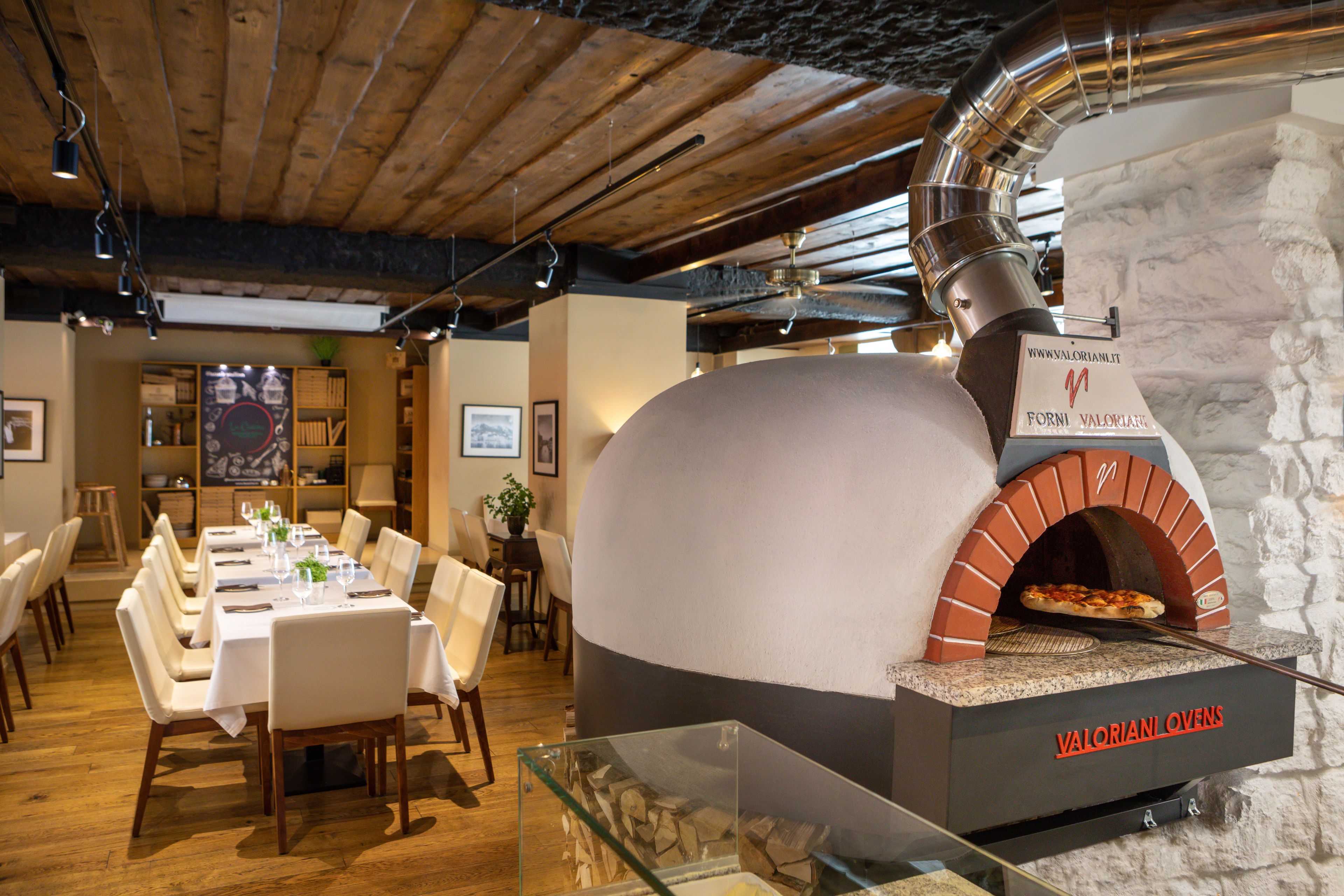 Un restaurant doté d’un four à pizza en briques, de tables et de chaises en bois.