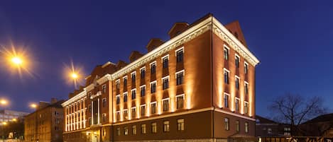 A large, historic building with multiple stories and a classic architectural style, featuring a prominent entrance and a well-lit facade.