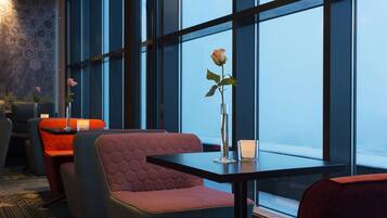 Un interior moderno con una zona de estar que incluye bancos acolchados y una mesa con un jarrón de flores.