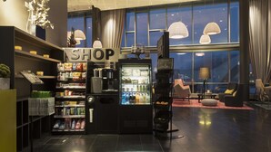 A hotel lobby with a self-service shop, vending machines, seating area, and large windows. - Scandic Narvik (Narvik)