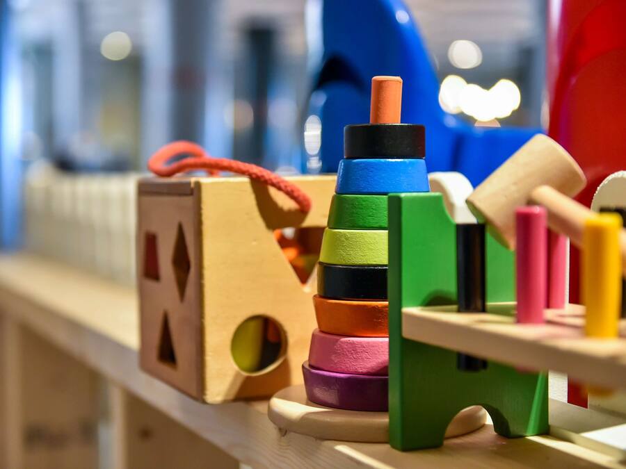 A wooden play structure with colorful blocks and a small house.