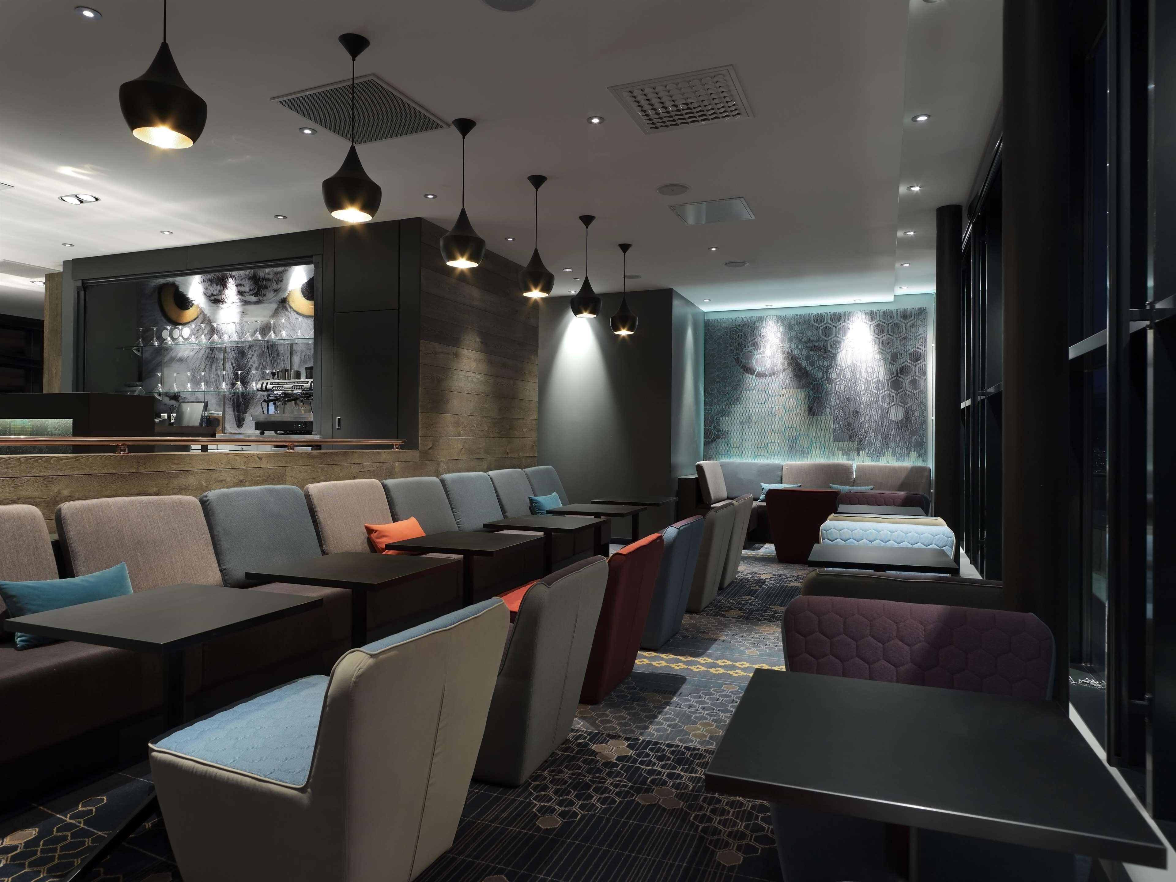 A modern lounge area with seating, a bar, and a patterned wall.