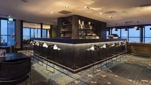 A bar area with a counter, stools, and a view of the city. - Scandic Narvik (Narvik)