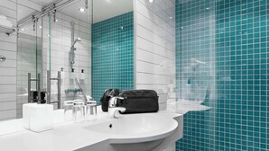 A modern bathroom with a white sink, a black bag on the counter, and blue-tiled walls.