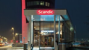 A tall building with a prominent 'Scandic' sign at the top and entrance.