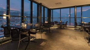 A modern dining area with large windows, wooden flooring, and black chairs. - Scandic Narvik (Narvik)