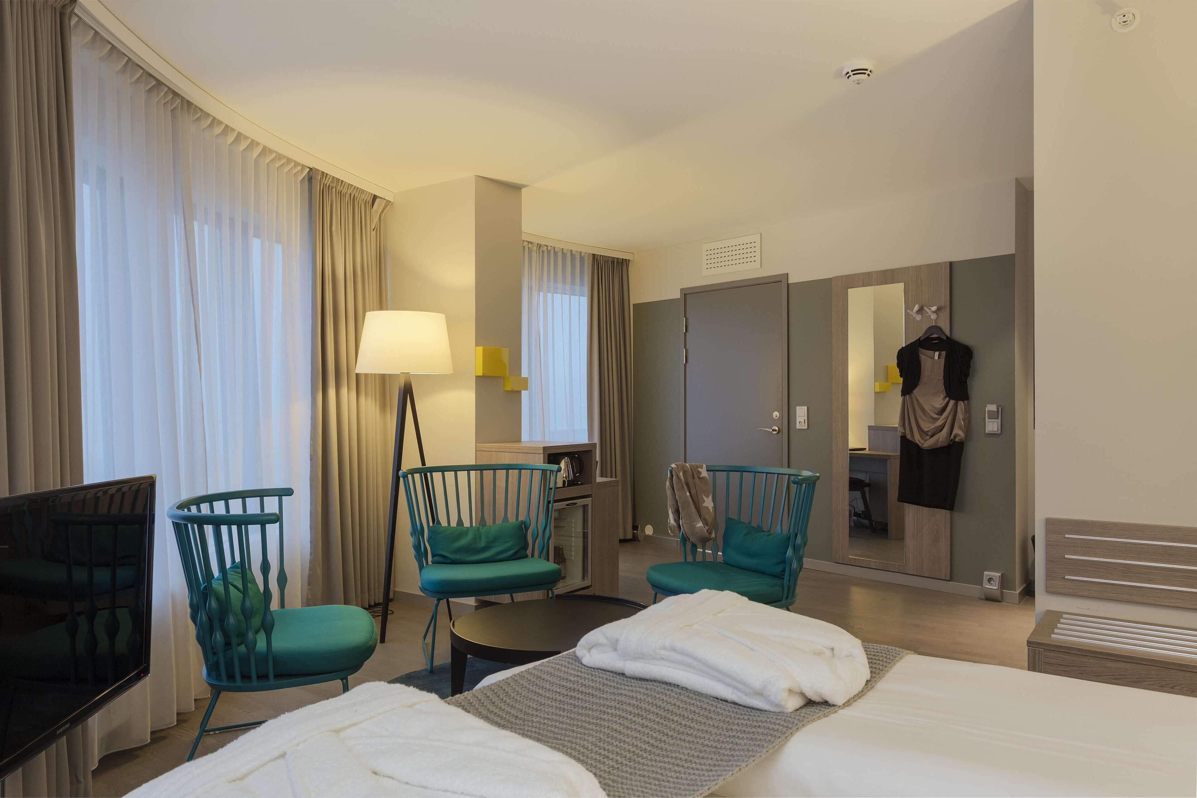 Ein Hotelzimmer mit zwei Betten, einem Fernseher, einem Schreibtisch und zwei Sesseln.