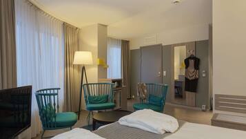 A hotel room with two beds, a TV, a desk, and two chairs.
