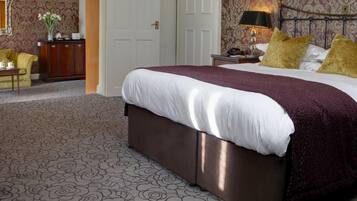 A bedroom with a large bed, a nightstand, a lamp, and a dresser.