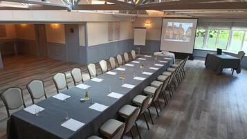 A conference room with a long table, chairs, a projector screen, and a presentation screen.