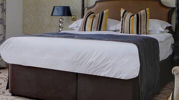 Una cama bien hecha con cabecera marrón, ropa de cama blanca y almohadas a rayas.