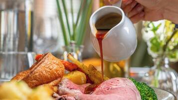 Ein Essen mit Braten, Kartoffeln und Gemüse, wobei Soße aufgieß wird.