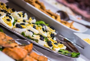 A buffet with various dishes including deviled eggs garnished with black caviar. - Soria Moria Hotell (Oslo)
