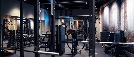 Une salle de sport équipée de divers appareils d’exercice, notamment des machines de musculation et des poids libres.