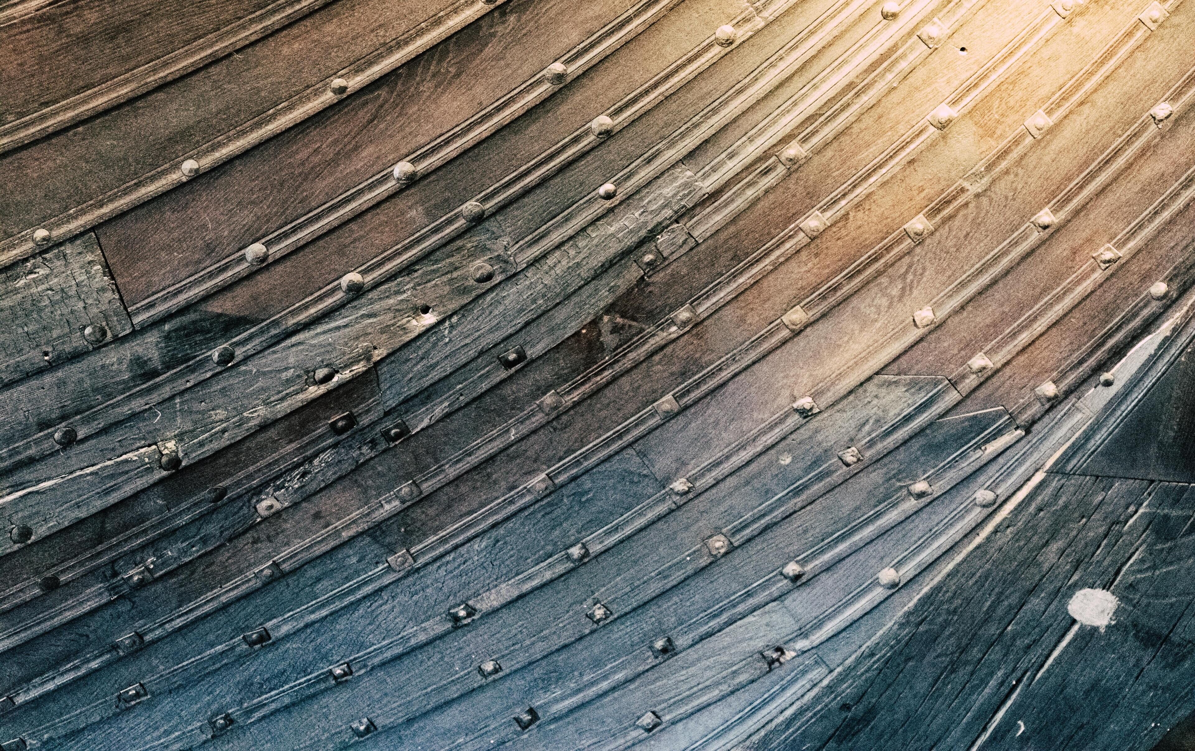 A close-up of a wooden surface with horizontal planks and rivets.