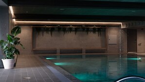 Una piscina interior con suelo de baldosas, una planta en maceta y un banco a lo largo de la pared.