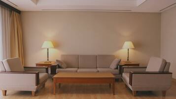 A living room with a sofa, two armchairs, a coffee table, and two lamps on side tables.