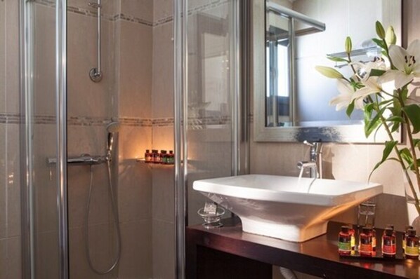 Un baño moderno con ducha de mampara de vidrio, un lavamanos blanco y un espejo encima.