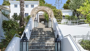 A set of stone steps leading to a white building with a stone archway.