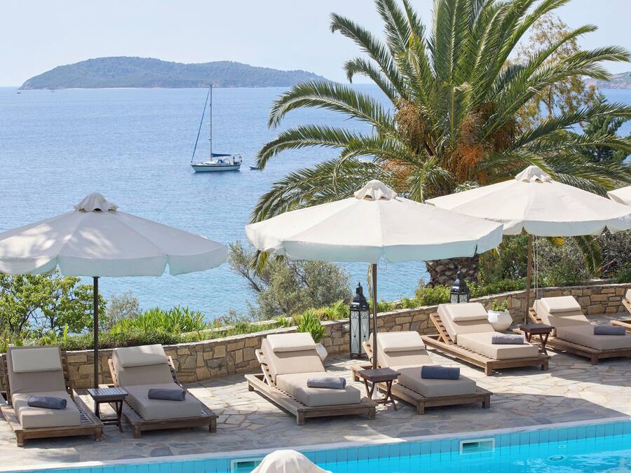 Una piscina al aire libre, sombrillas, sillones reclinables de piscina