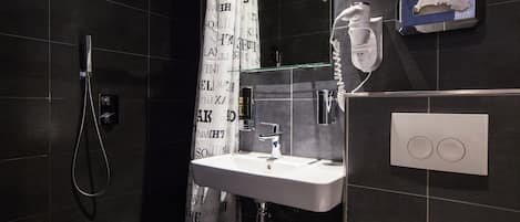 A modern bathroom with a shower, a sink, and a towel dispenser.