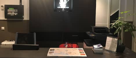 Un comptoir d’accueil avec une carte, un sac rouge, une plante et un panneau.