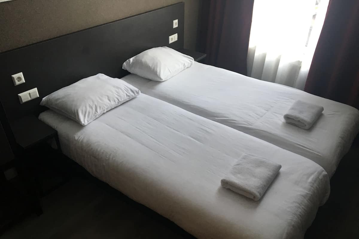 Una cama doble con sábanas y almohadas blancas, una mesita de noche y un cabecero.