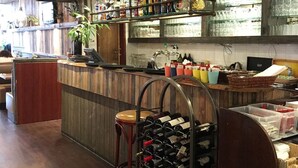 Una zona de bar con paneles de madera, una bodega y una variedad de botellas y copas.
