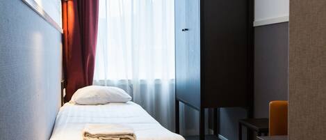 Una habitación de hotel con una cama, un escritorio y una silla.