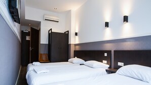 Una habitación de hotel con dos camas, un armario, una silla y aire acondicionado instalado en la pared.
